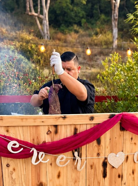 Smoked Delights pitmaster pulling tri-tip from the smoker at an event